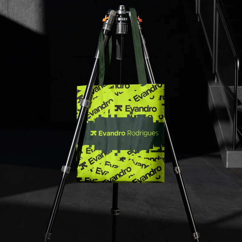 Sacola verde-limão com a identidade visual da marca, pendurada em um tripé em ambiente escuro